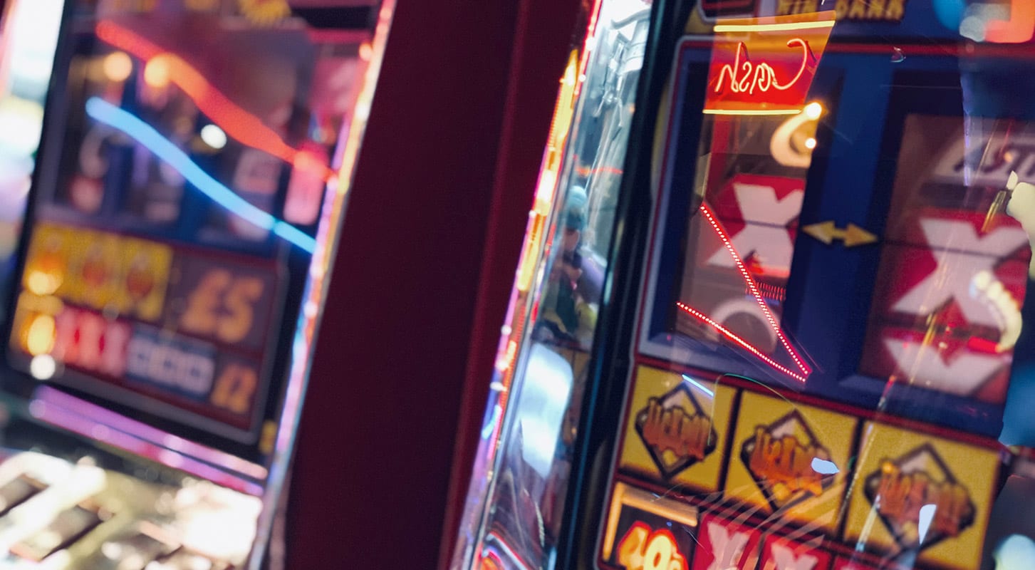 Close-up of colorful slot machines in a casino, showcasing spinning reels and bright lights.
